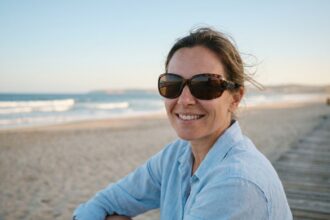 Femme portant des lunettes de soleil protectrices UV au bord de la mer en été